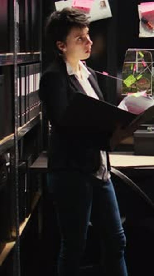 Focused Woman Reviewing Documents in File Room