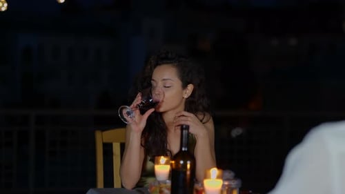 Woman drinking wine on a rooftop at night