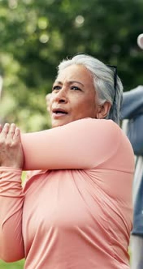 Senior woman, fitness and stretching with group in park for physical activity or outdoor exercise