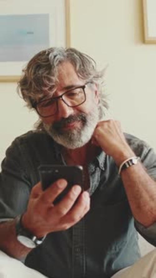 Adult Man Using Phone on Sofa at Home