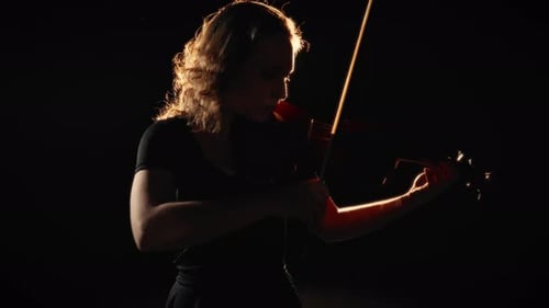Woman Playing Violin in Dramatic Lighting