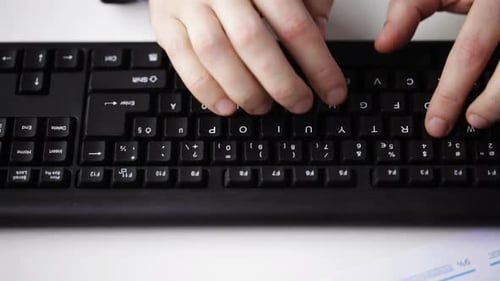 Hands typing on a computer keyboard in office
