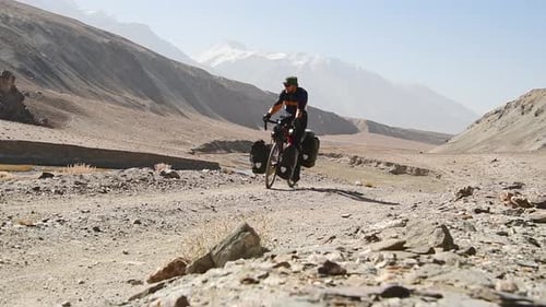 Cyclist Rides Bike Through Remote Desert Mountain Pass