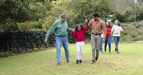 Ao ver o avô e o pai balançando as mãos da criança, família extensa passeando no gramado apontando para frente