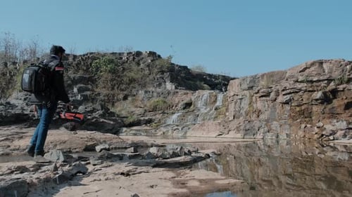 And Indian Biker walking across a waterfall stream