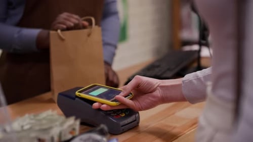 Sales Assistant Accepting Payment by Smartphone App and Thanking Customer