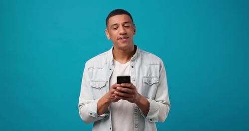 Smiling Man Holding Mobile Phone on Teal Background