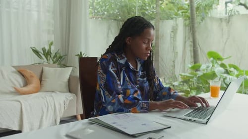 Woman Works on Laptop at Home in Sunny Room