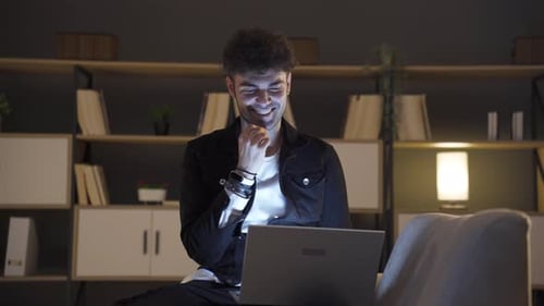 Young Man Typing on Laptop Computer at Night