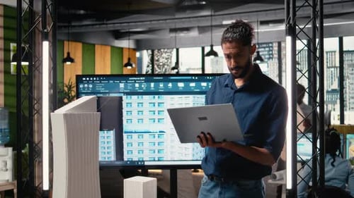Architect working with building models and laptop in office