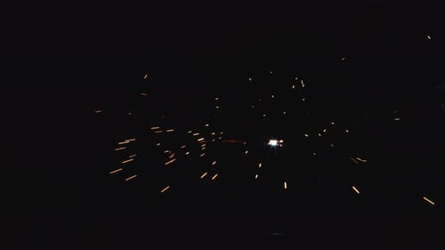 A blacksmith with a welding mask and welders leathers, is welding metal products in the garage, fire