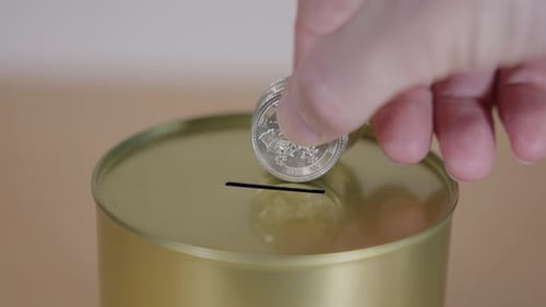 Depositing Coin into Metallic Gold Coin Bank