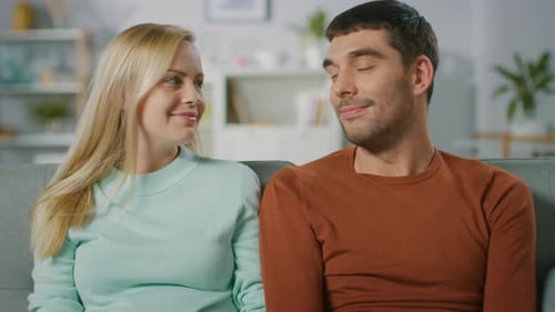 Affectionate Couple Smiling and Holding Hands on Sofa