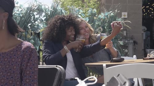 Smiling women taking a selfie together outside
