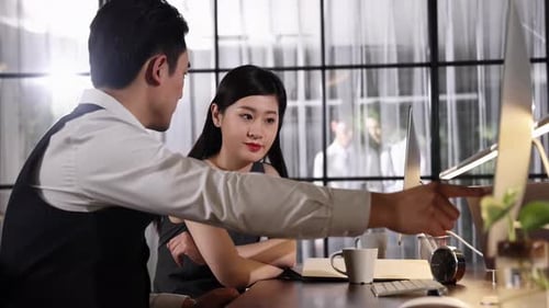 Professionals Discuss Work at Desk in Modern Office