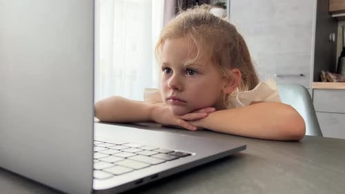 Girl Watching Laptop Screen at Kitchen Table