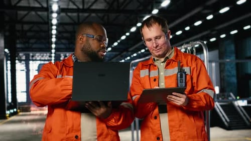 Colleagues Use Laptop and Tablet to Guide Personnel During Fabrication