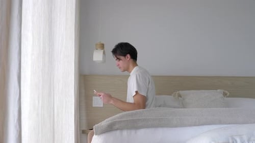 Man Texting On Phone While Sitting On The Bed. - wide
