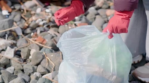 Voluntario llenando una bolsa con basura y diferentes residuos, reciclaje y problema de contaminación plástica