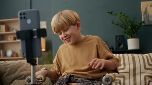 Boy with Skateboard Talking to Camera Phone Indoors