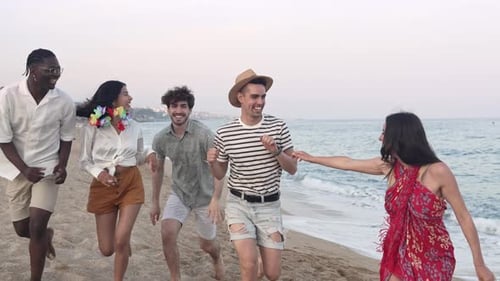 Group Of Multi Ethnic Happy Friends Having Fun Running Along Beach in Summer
