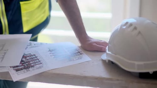 Construction Specialist in Professional Uniform Working with Drawings Documentation