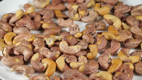 Cashew Nuts Falling onto a White Surface