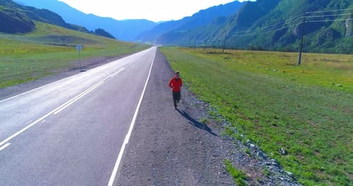 Low Altitude Flight in Front of Sporty Man at Perfect Asphalt Road
