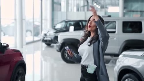 Young woman scattering money in a car dealership and dancing