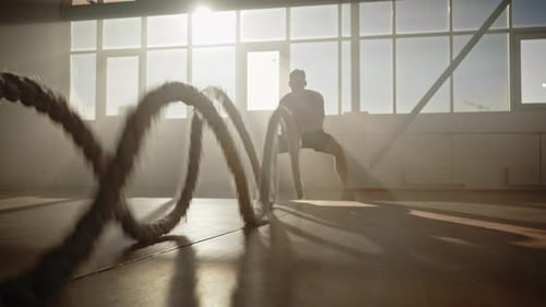Motivierter Athlet: Springen, Hocken, Hocken und Longieren, während er beim Ausdauertraining mit dem Seil kämpft