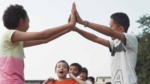 Slow motion of group of children playing games in playground and pass under the arm of two children