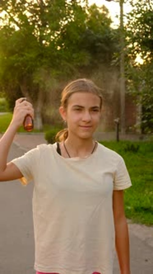 Girl Sprays Hair Product on Head Outdoors