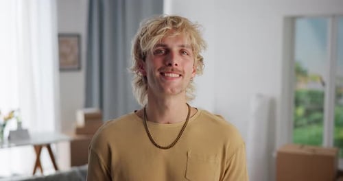 Man, face and smile in new home with boxes, moving and excited for property investment in lounge