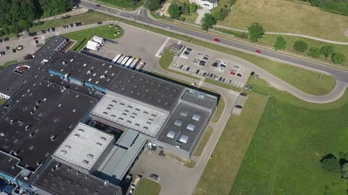 Zoom Out Aerial Shot of Industrial Warehouse/ Storage Building/ Loading Area where Many Trucks Are L