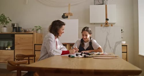 View From the Side of a Brunette Woman and Her Daughter Doing Hobbies and Drawing at a Table in the