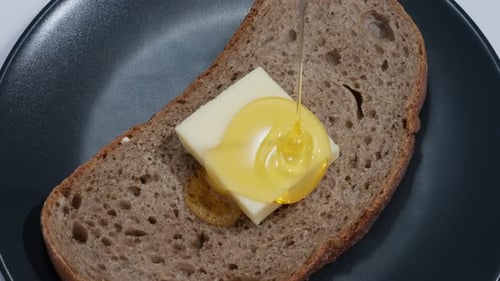Honey Poured on Buttered Bread Slice on Plate