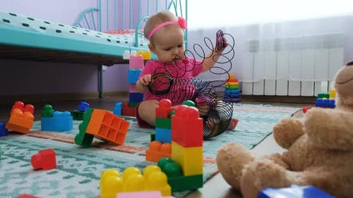 Baby Girl Playing with Colorful Toy Spring on Rug