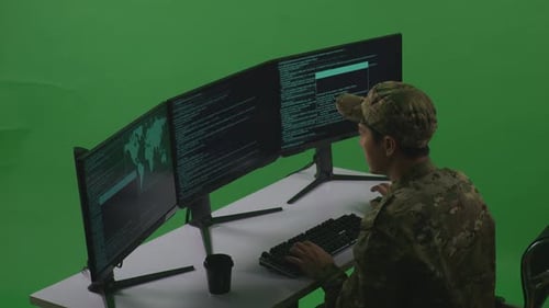 Side View Of Asian Man Soldier Using Computer To Write Code With Multiple Screens In Green Screen