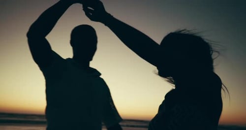 Silhouette, sunset and couple are dancing on beach for love, freedom and travel together