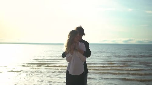 A Couple Embracing Each Other Tenderly at Sunset While Standing on a Beautiful Beach