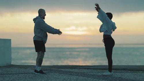 Multiethnisches Paar dehnt sich beim morgendlichen Training am Meer