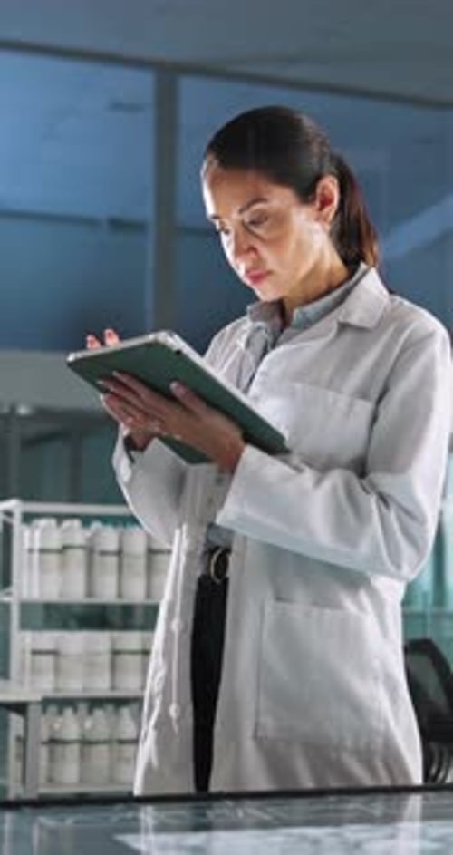 Woman in Lab Coat Reviews Tablet Data