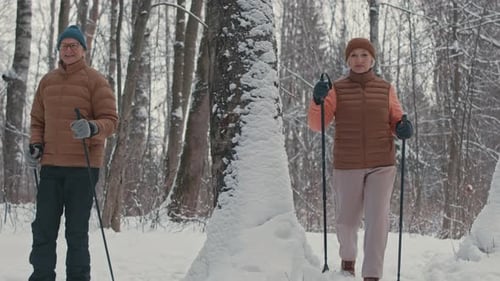 Active Couple of Boomers Nordic Walking in Winter Forest