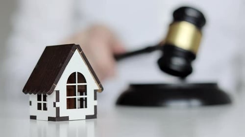 Real estate auction concept. Gavel and wooden house on the background.