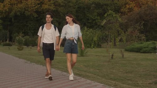 Couple Walking Hand-in-Hand Through Grassy Park