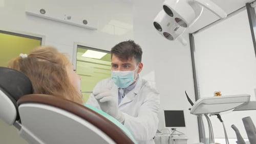 Dedicated Male Dentist Examining a Little Girl's Teeth in a Bright Clinic