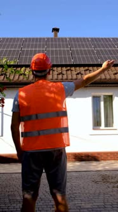Man points to solar panels on rooftop