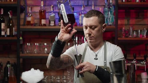 Un barman sérieux verse gracieusement de l'alcool dans un jigger