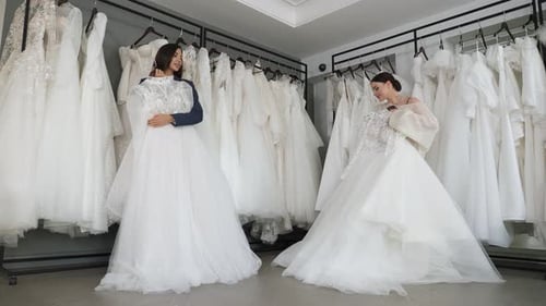 Duas noivas felizes escolhem seu vestido de noiva no salão de casamento