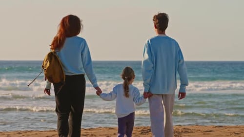 A Mother with Her Children a Teenage Son and a Little Daughter Walks Along the Ocean Shore at Sunset